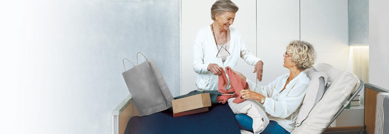 A service user and her friend, the service user is lying on a medley ergo profile bed.