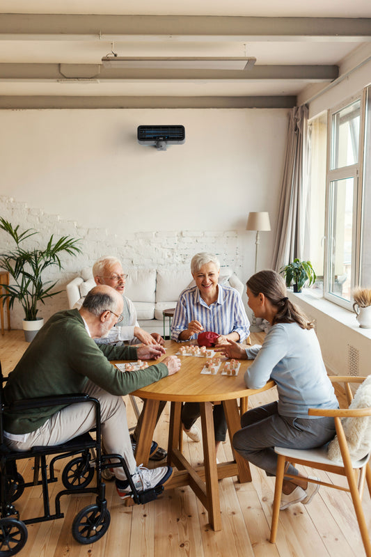 A care home showing four people sitting at a table with an ODEO upperviolet unit attached to the wall.