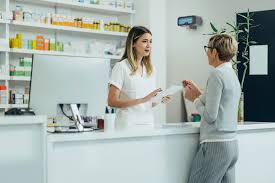 Pharmacist assisting a customer in a pharmacy setting with an Odeo Uppervioler Air Purifier in use.